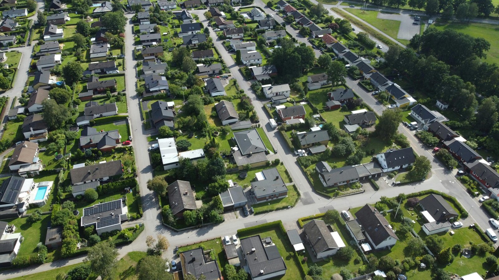 Aerial shot of a lush suburban neighborhood with green gardens and houses.
